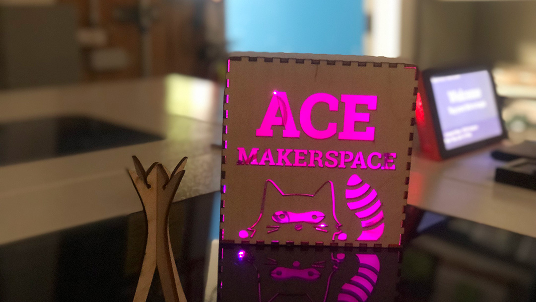 Lit up "Ace Makerspace" laser-cut sign, mini-burning man effigy