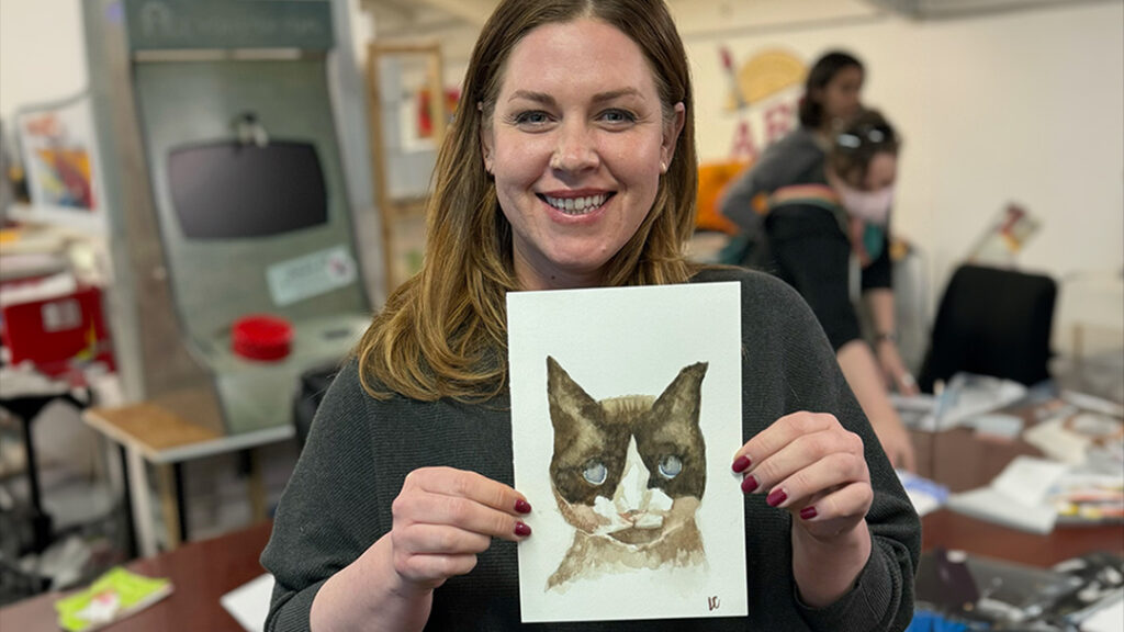 Person holding watercolor cat portrait.