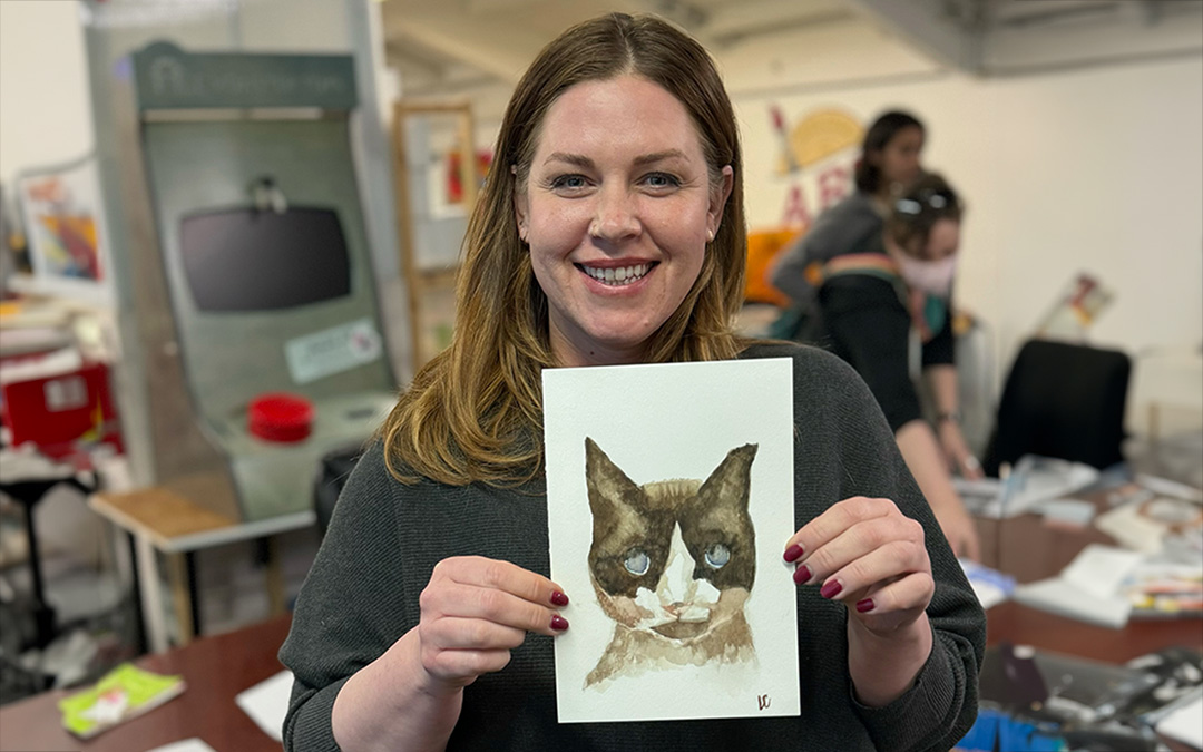 Person holding watercolor cat portrait.