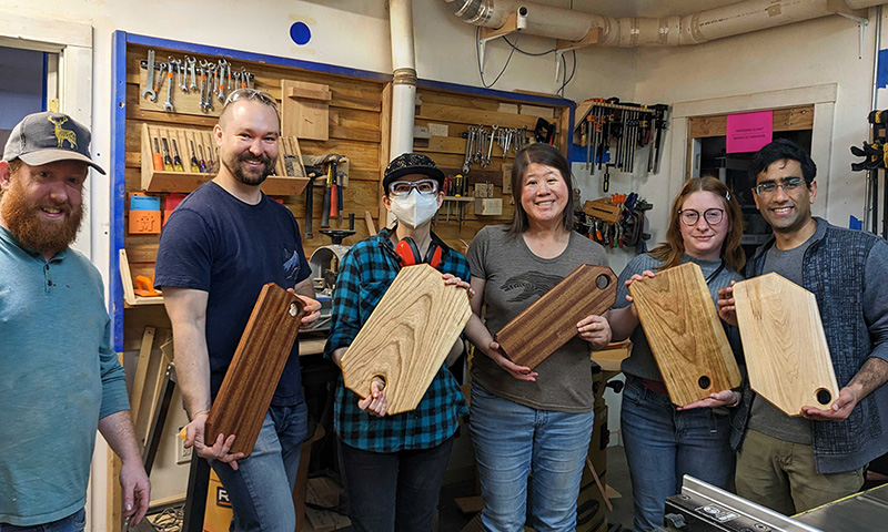 Group posing with solid wood cutting boards.