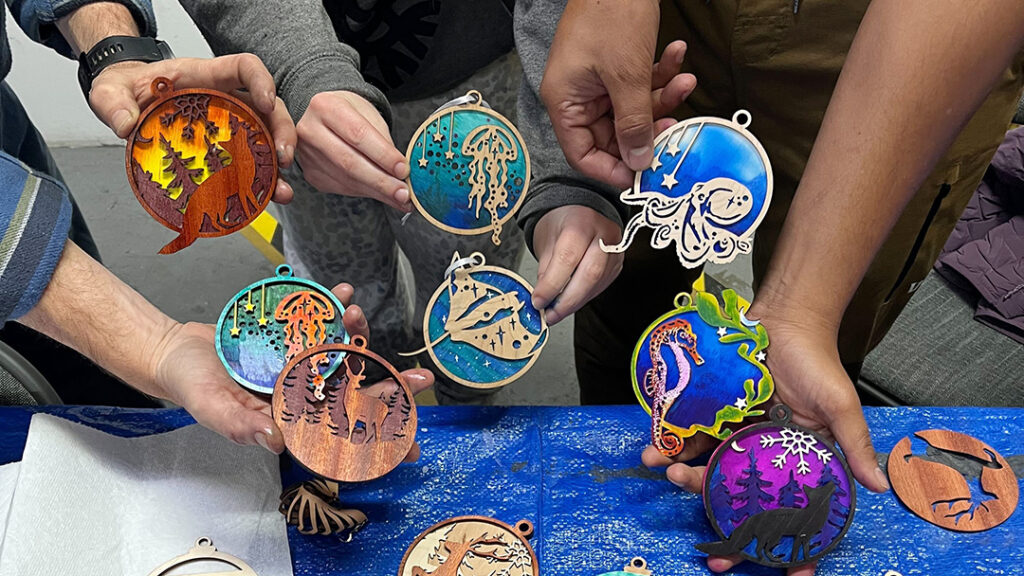 Hands holding vivid laser-cut ornaments with ocean themes.