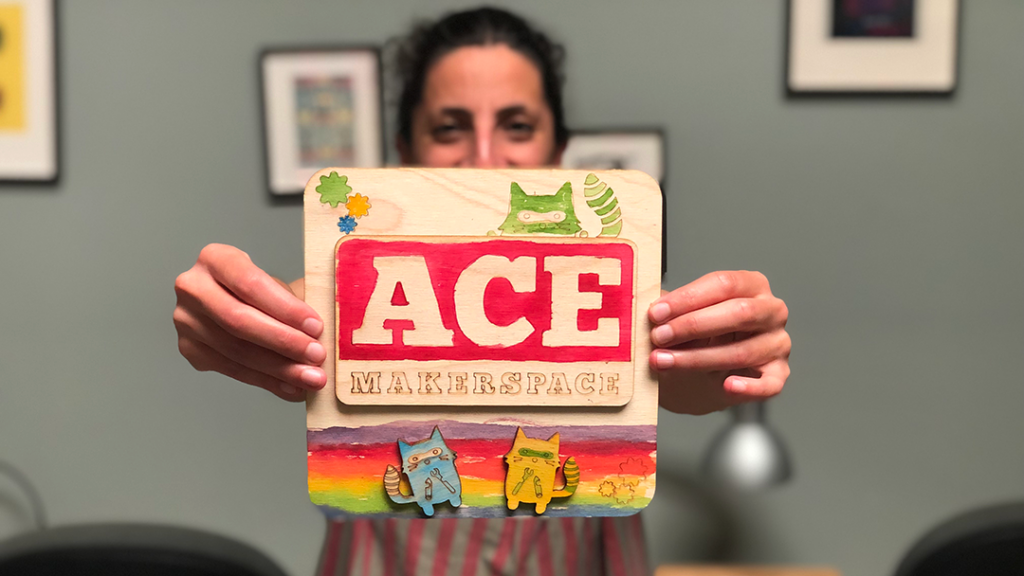 Person holding Laser-cut wood collage, "ACE" with critters.