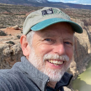 Person in hat smiling outdoors. 