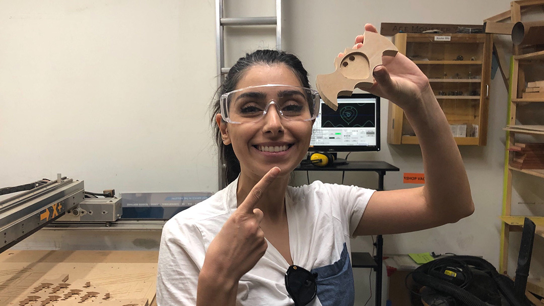 person smiling in front of CNC router with bat coaster