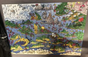 A completed magic jigsaw puzzle titled "The Happy Isles" on a table in textiles/coworking